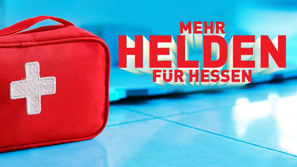 Eine Erste-Hilfe-Tasche steht auf blauem Fliesenboden. Daneben steht in roter Schrift "Mehr Helden für Hessen".