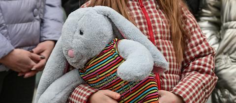 Ein aus der Ukraine geflüchtetes Mädchen hat ihren Plüschhasen im Arm.