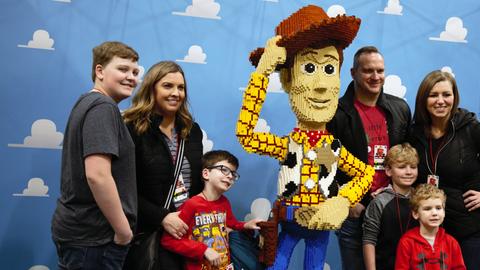 Eine Familie macht ein Foto mit einer lebensgroßen Lego-Figur von Sheriff Woody aus Toy Story 