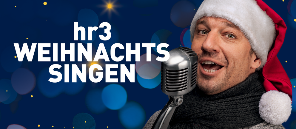 hr3 Moderator Tobias Kämmerer singt mit Weihnachtsmütze auf dem Kopf in ein Mikro.