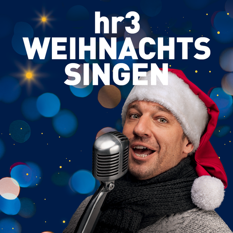 hr3 Moderator Tobias Kämmerer singt mit Weihnachtsmütze auf dem Kopf in ein Mikro.
