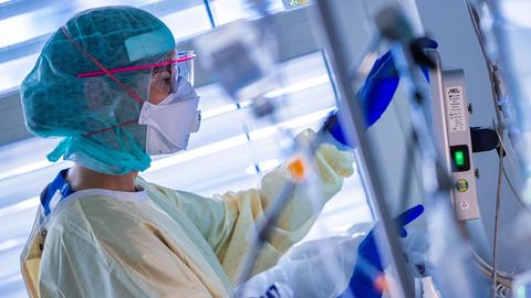 Eine Krankenschwester dokumentiert auf der Intensivstation neben dem Bett eines Corona-Patienten die Behandlungsschritte