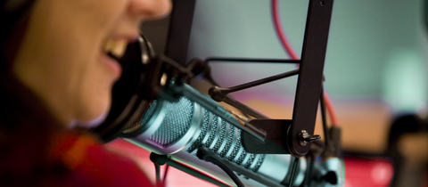 Eine Frau spricht in einem Hörfunkstudio in ein Mikrofon