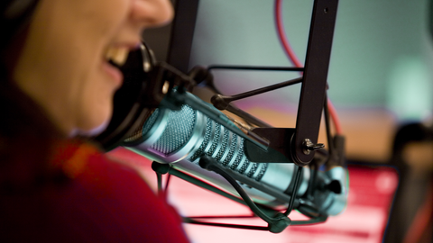 Eine Frau spricht in einem Hörfunkstudio in ein Mikrofon