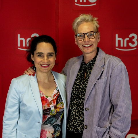 Yael Adler und Bärbel Schäfer lächeln im hr3 Studio in die Kamera.