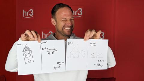 Tobi hält Zeichnungen von Leony und ihm selbst in die Kamera.