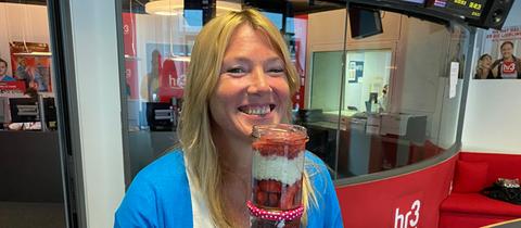 Tanja präsentiert lachend ihre Erdbeer Overnight Oats im Einmachglas