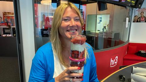 Tanja präsentiert lachend ihre Erdbeer Overnight Oats im Einmachglas