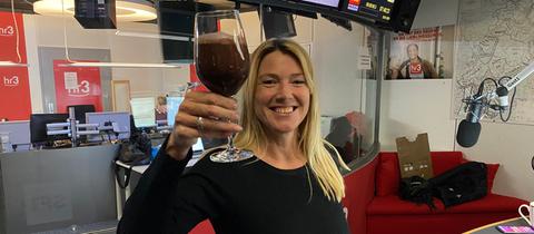 Tanja und Tobi halten lächelnd ein Glas mit einem schokobraunen Shake in den Händen.