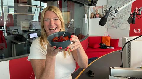 Tanja hält grinsend die Schüssel voller Erdbeeren in die Kamera