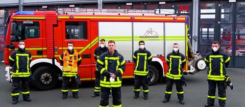 Die Männer der Feuerwehr Hanau steht vor einem ihrer Löschfahrzeuge