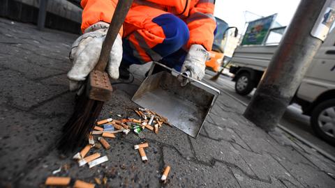 Ein Müllarbeiter entsorgt Zigarettenstummel auf der Straße